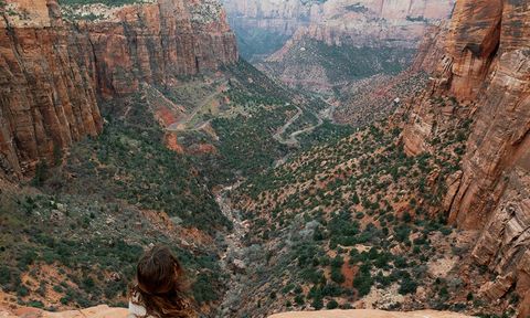 A woman sitting on the edge of a rock overlooking a ravine