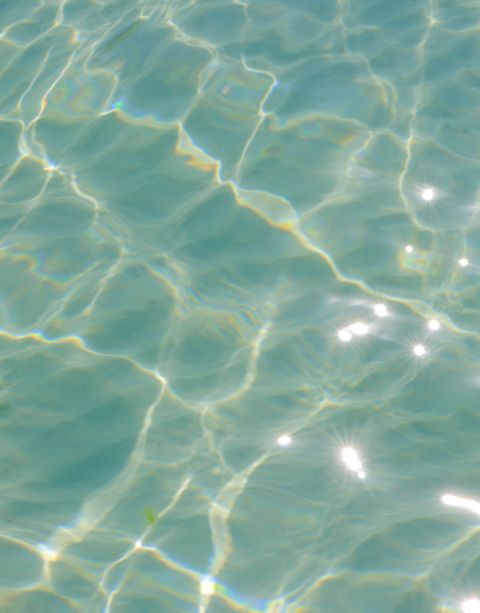 Sunlight sparkles on clear turquoise water, creating a wavy, textured surface pattern