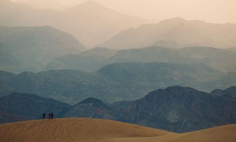 A sandy hill in shadow and mountains in the background