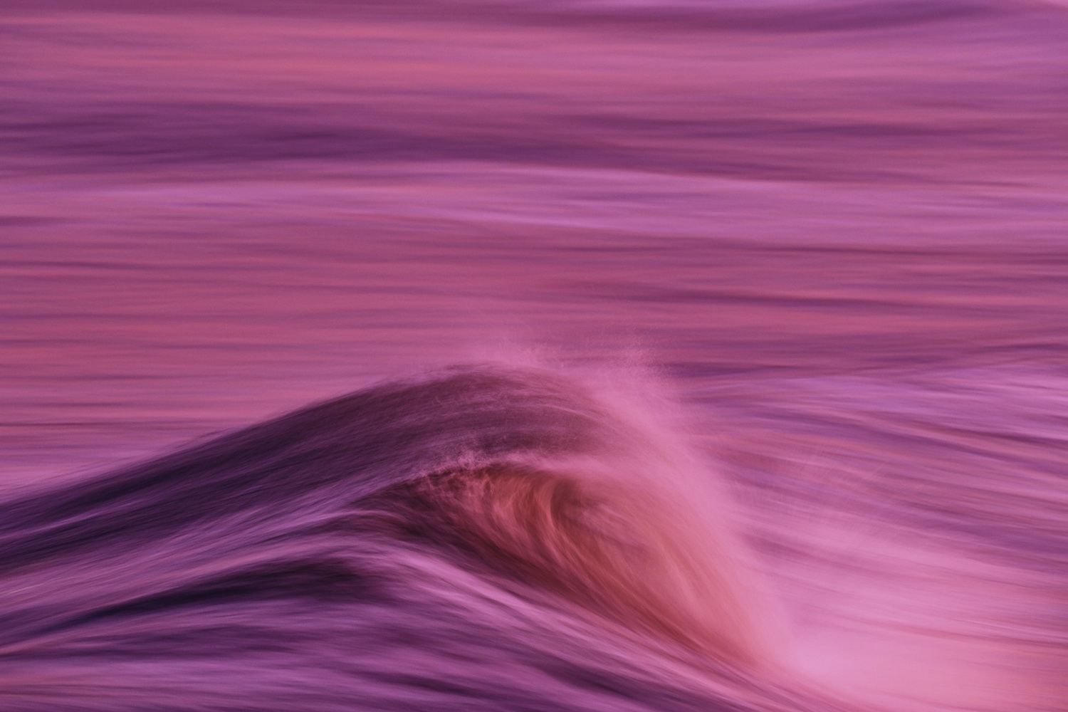 A blurred, abstract image of ocean waves in a vivid purple hue, showing motion and texture in a dreamy, serene atmosphere
