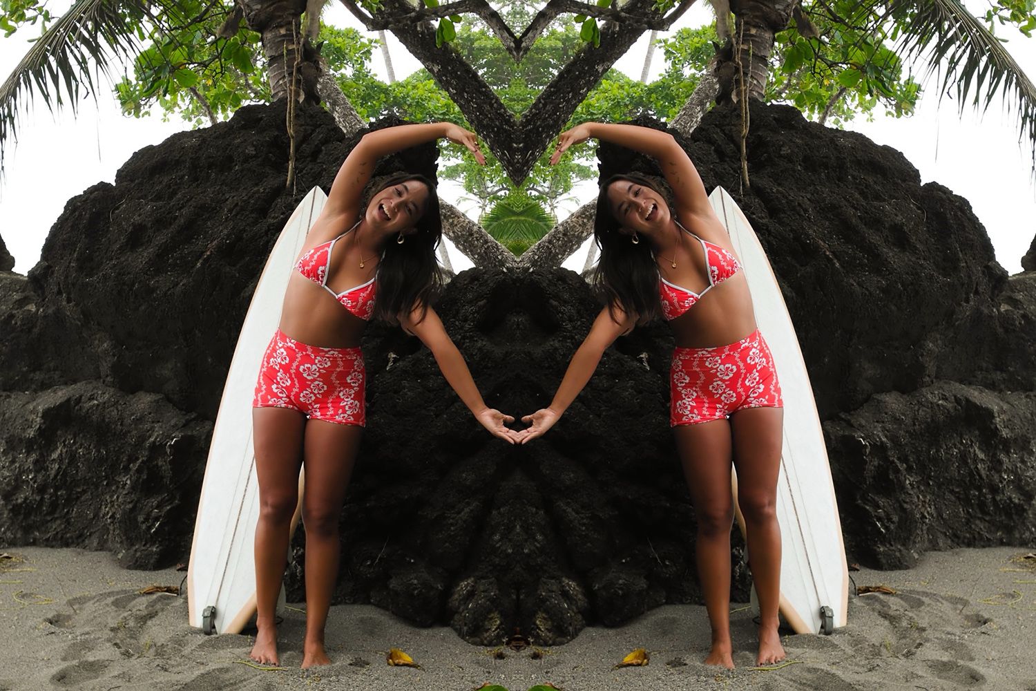 Woman in red swimsuit posing with a surfboard on a beach, mirrored image effect, surrounded by rocks and greenery