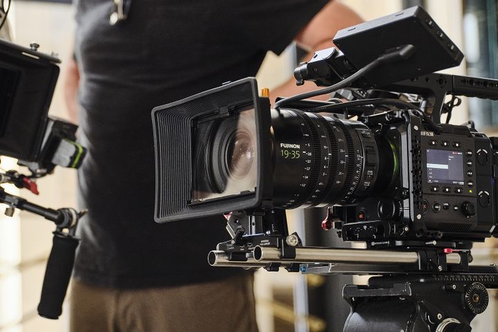 Close-up of a professional video camera with a large lens, mounted on a rig
