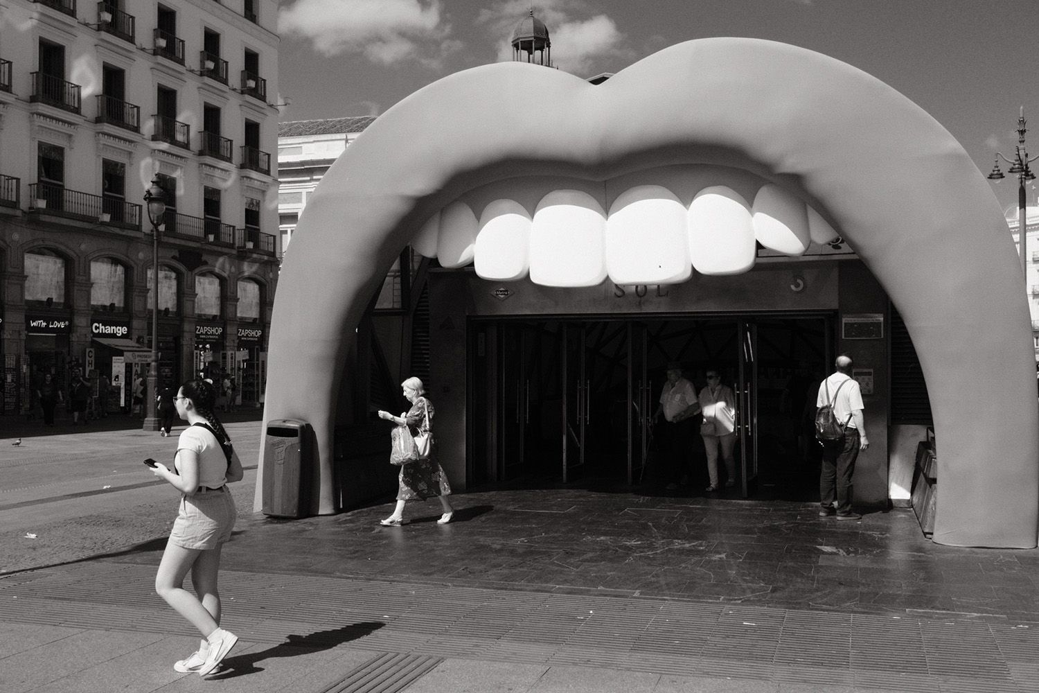 People walk near a subway entrance shaped like a giant mouth