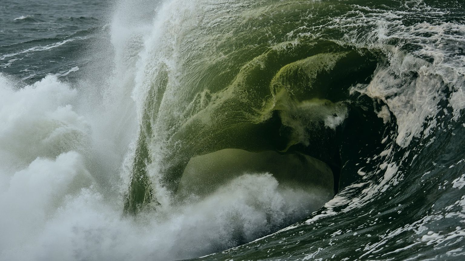 A massive ocean wave crashing, with white foam and deep green water swirling dramatically, creating a powerful and dynamic scene