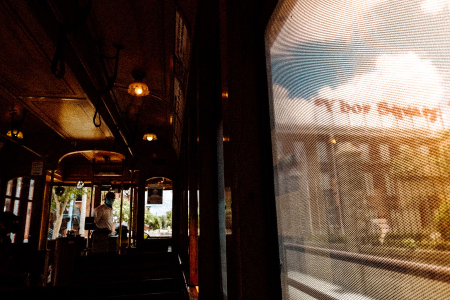 Interior of a vintage tram with warm lighting, with a street scene visible through the window. Interior of a vintage tram with warm lighting, with a street scene visible through the window.